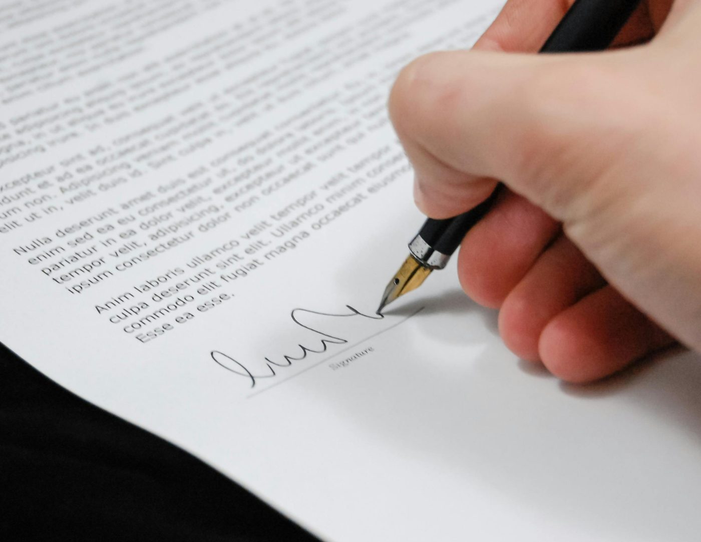 A nurse signing a policy document with a fountain pen